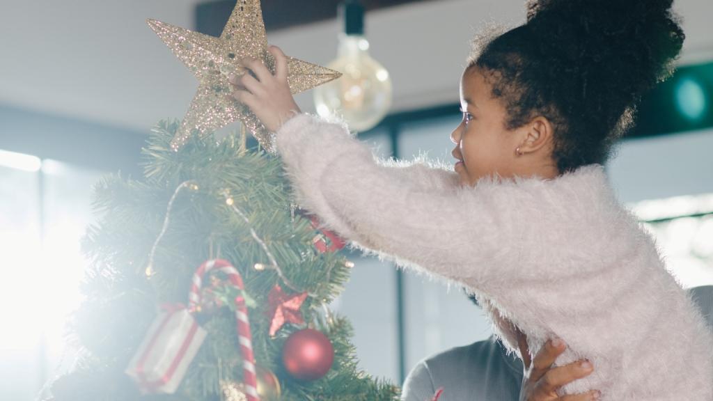 menina pondo a estrela no topo da árvore de natal, decoração típica do fim de ano